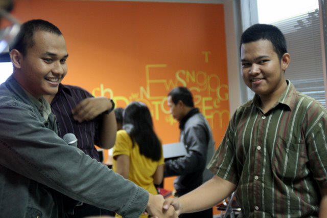 Dua pria tersenyum berjabat tangan, berjuang untuk hak-hak penyandang disabilitas di Indonesia.